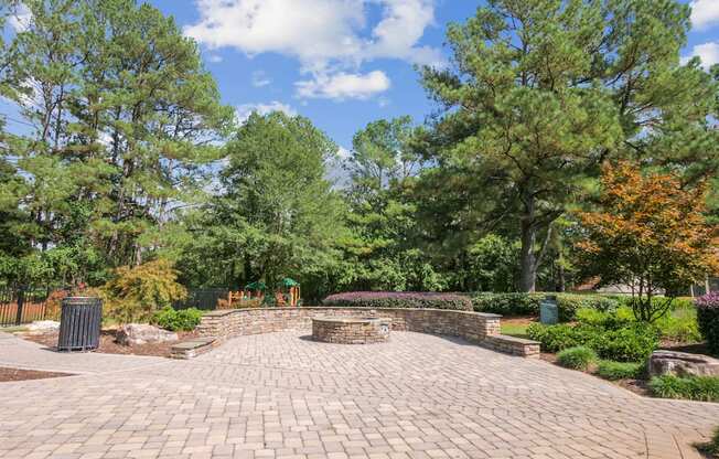 A brick walkway leads to a small gazebo in a park.