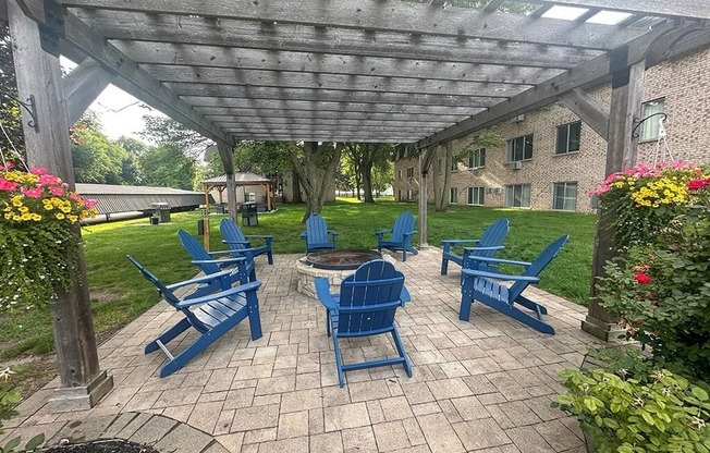 a patio with blue chairs and a fire pit