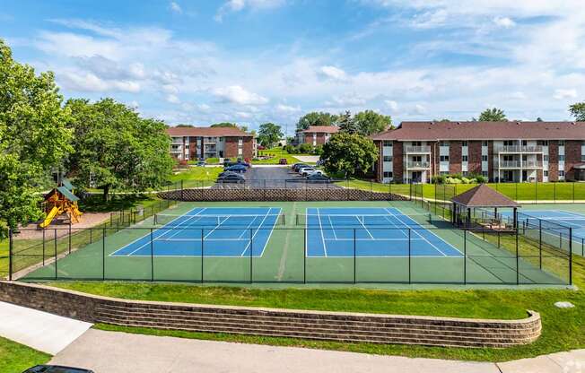 A tennis court surrounded by a fence and a brick wall.