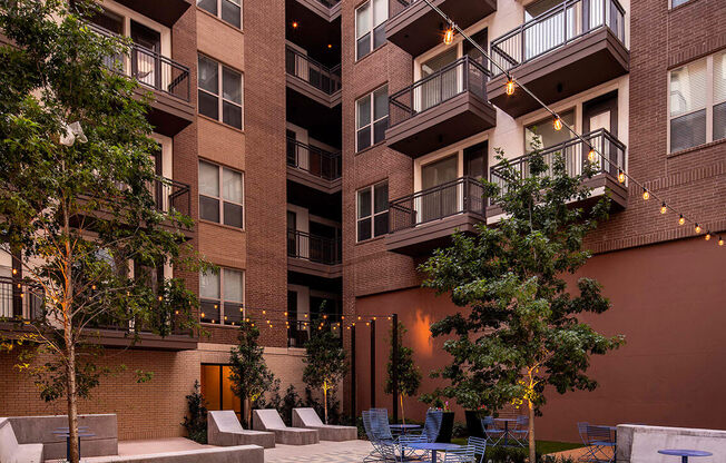 A courtyard with tables and chairs surrounded by apartment buildings.
