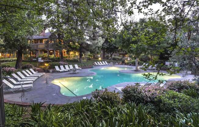 a large swimming pool with chairs and trees