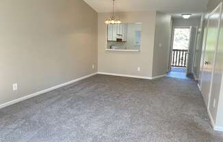 A large empty room with a grey carpet and a mirror on the wall.