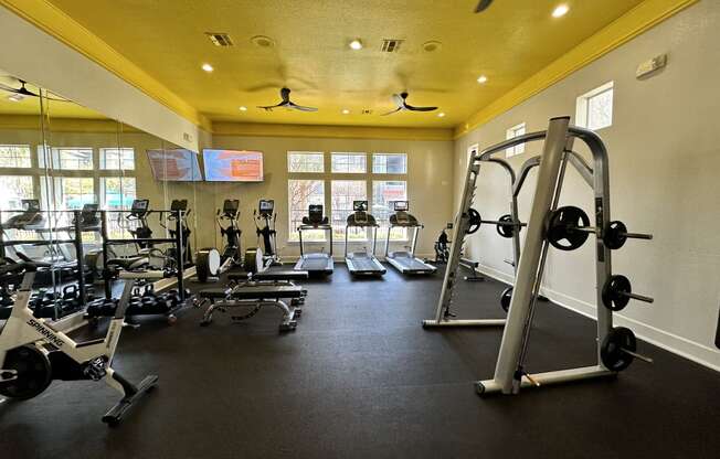 a gym with weights and cardio equipment on the floor and windows