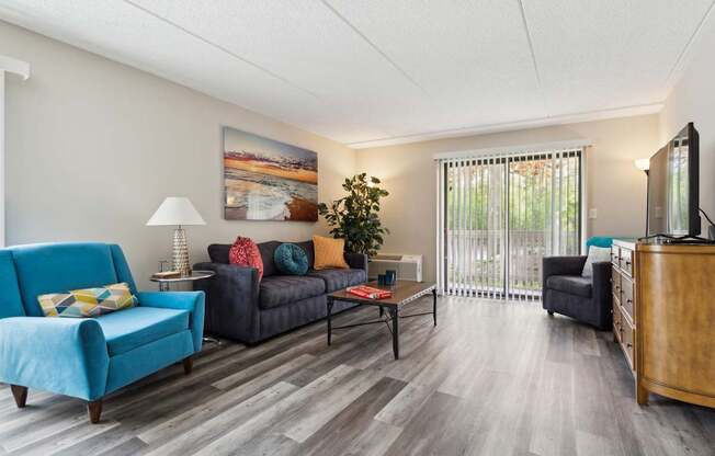A living room with a blue couch, a black sofa, a coffee table, and a television.