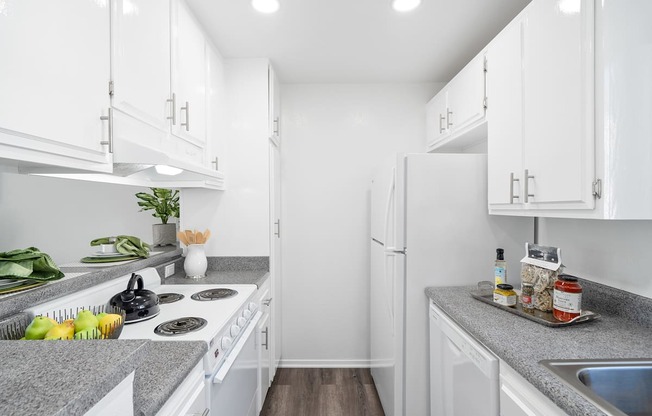 a white kitchen with white appliances and granite counter tops