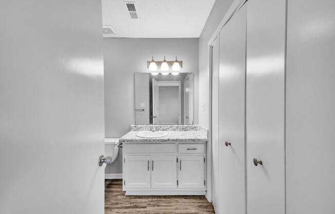 a bathroom with white cabinets and a sink and a mirror