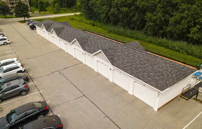 A parking lot with cars and a white building with grey roofs.