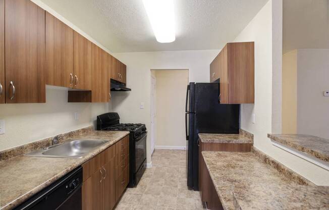 a kitchen with a black refrigerator freezer next to a stove top oven