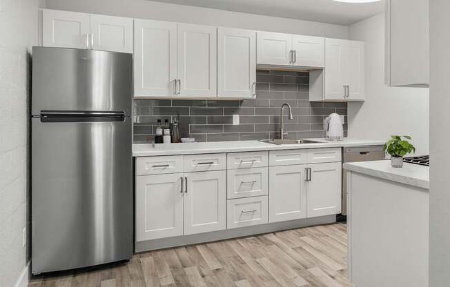 A modern kitchen with a stainless steel refrigerator and white cabinets.