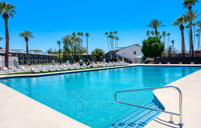 a swimming pool with palm trees and a building in the background at Presidio Palms Apartments, Arizona, 85701