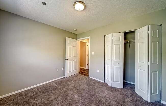 a empty room with closet doors and a door to a hallway