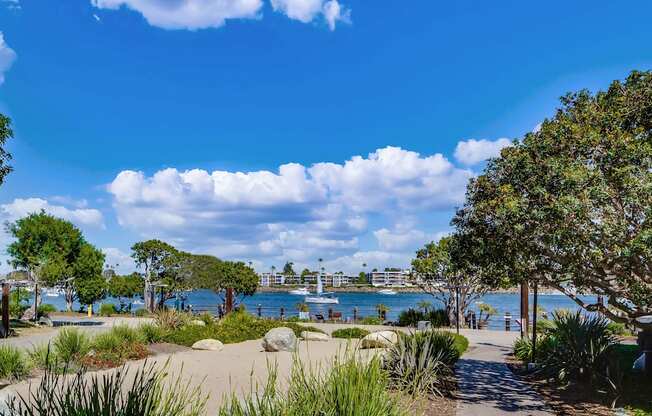 A pathway leads through a grassy area to a body of water with boats.