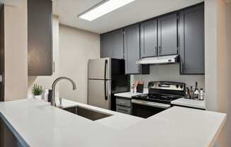 Model kitchen with dark cabinets and light countertops