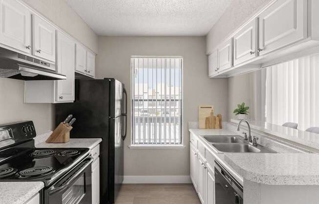 A kitchen with black appliances and white cabinets.
