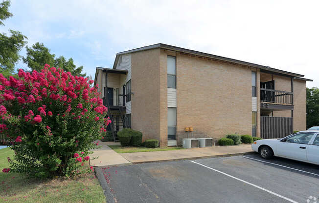 A white car is parked in front of a brick building.