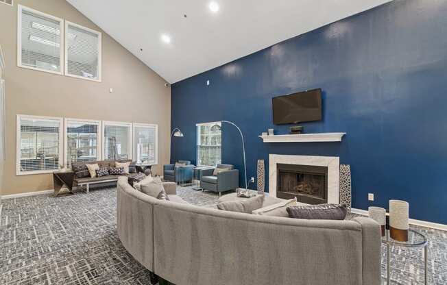 Clubhouse lounge area with couch and a TV above the fireplace at Woodmere Trace apartments in Duluth, GA