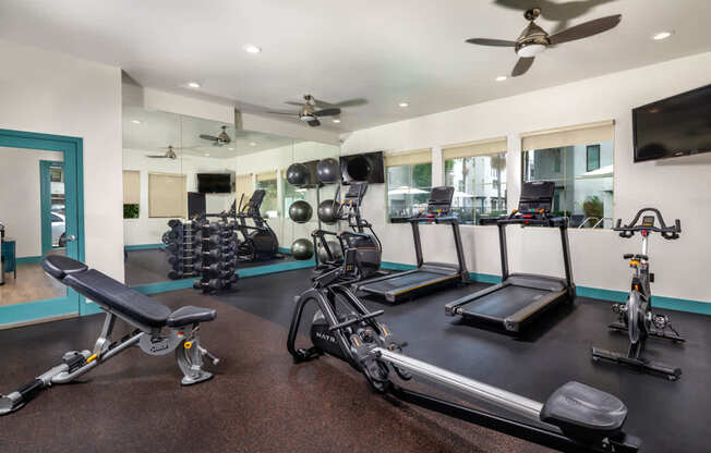 A gym with a variety of equipment including treadmills, exercise bikes, and weights.