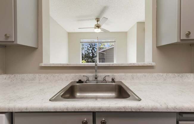 A kitchen with a marble countertop and a stainless steel sink.