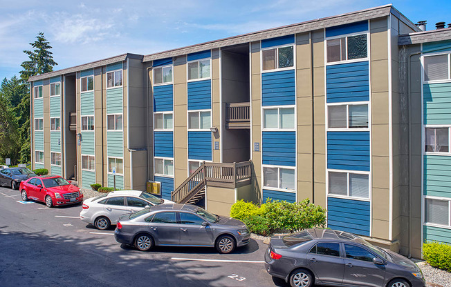 Community apartments painted shades of blue and beige with parked cars along the landscaped path.