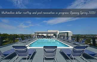 A swimming pool surrounded by lounge chairs on a rooftop.