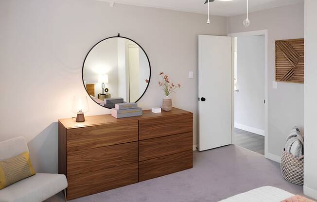 round mirror above a wood dresser