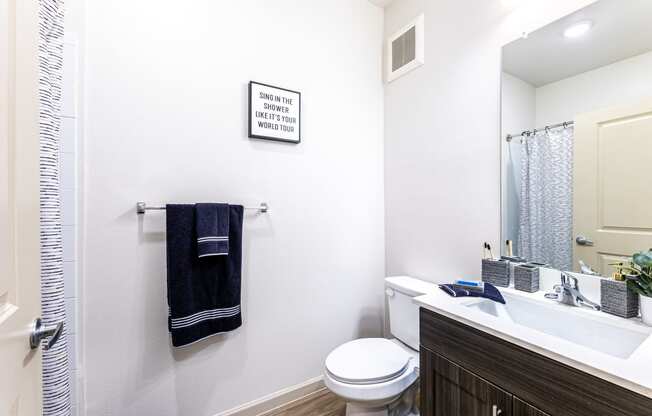 Bathroom with a toilet sink and shower and a mirror at The Parker Austin, Pflugerville, TX