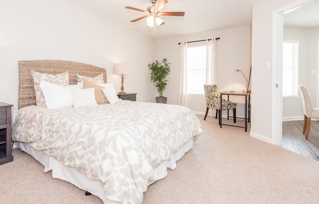 A bedroom with a large bed and a ceiling fan.