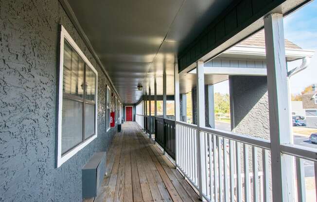 a long porch with wood floors and a red door in the distance