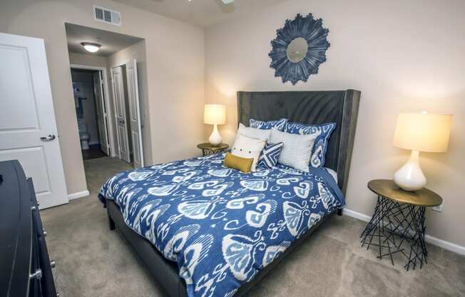 a bedroom with a bed with blue and white comforter and pillows