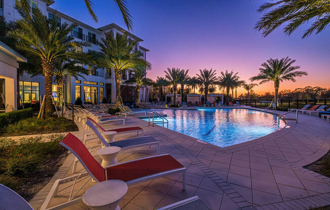 A pool surrounded by palm trees and lounge chairs.