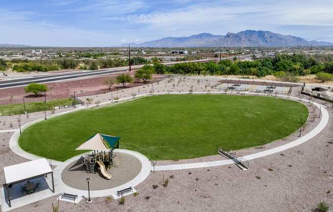 A playground with a green slide and a white canopy is surrounded by a circular path.