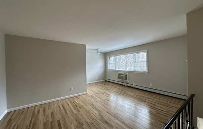 A room with wooden floors and a window with blinds.
