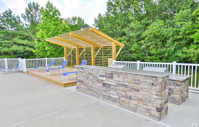 A wooden pavilion with a stone wall and two chairs.