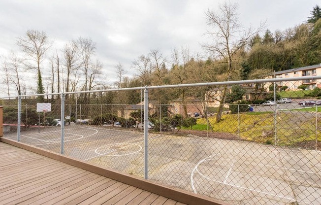 a basketball court in a backyard behind a fence