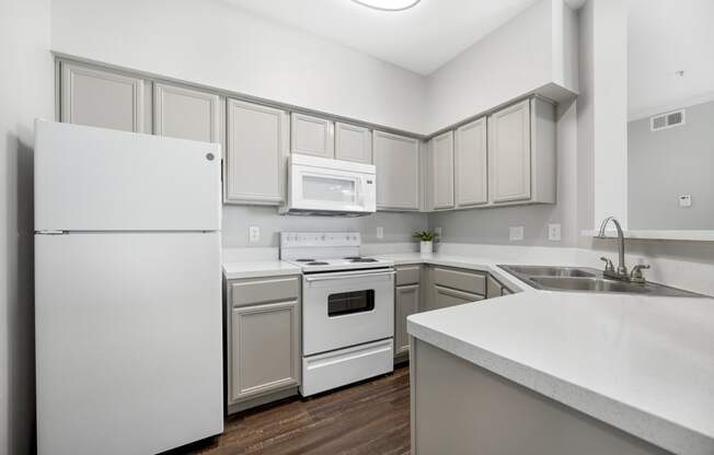 an empty kitchen with white appliances and white cabinets