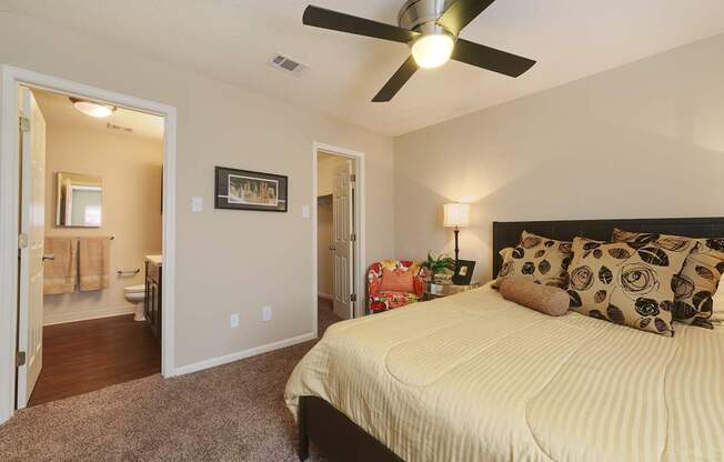 A bedroom with a bed, pillows, and a ceiling fan.