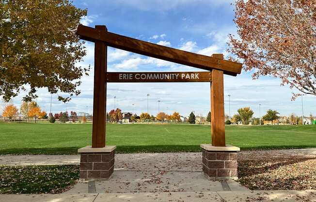 A wooden sign that says Erie Community Park stands in front of a field.