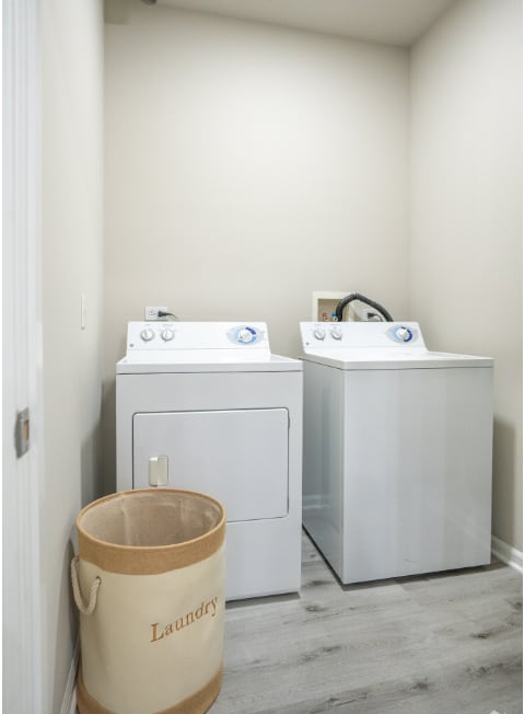 a laundry room with two washing machines and a bucket on the floor