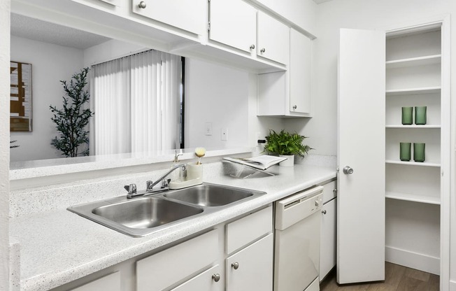 a kitchen with white cabinets and a stainless steel sink