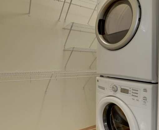Washer dryer stack in closet with shelving in the Flat D, studio apartment floor plan at Coze Flats