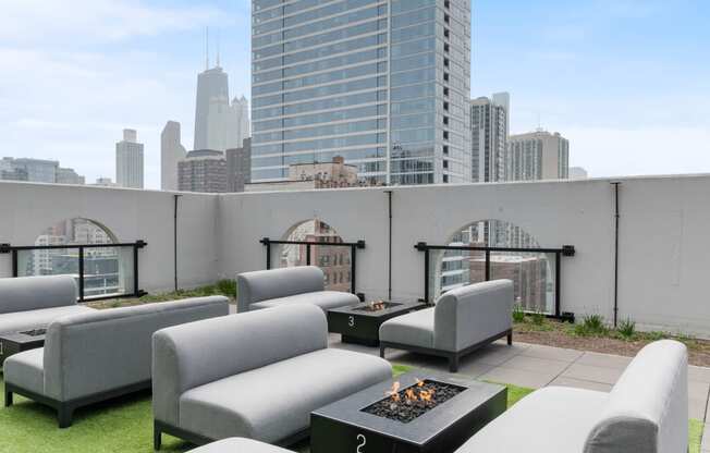 a terrace with couches and a fire pit on the top of a building
