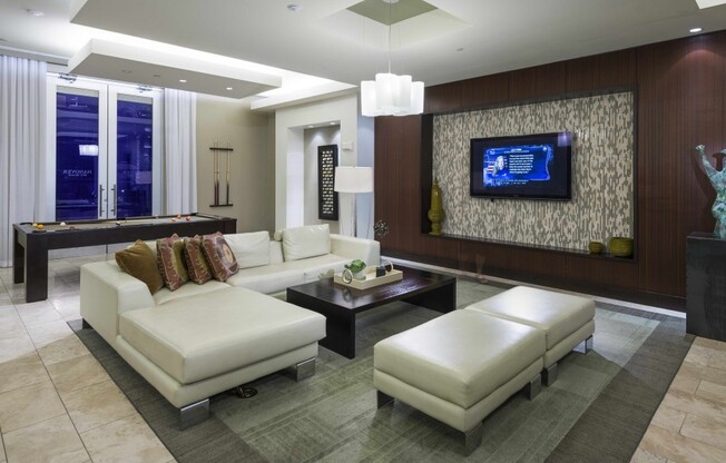 Lounge with a pool table, white leather sectional seating, HDTV, wood-paneled walls, and modern sculptures