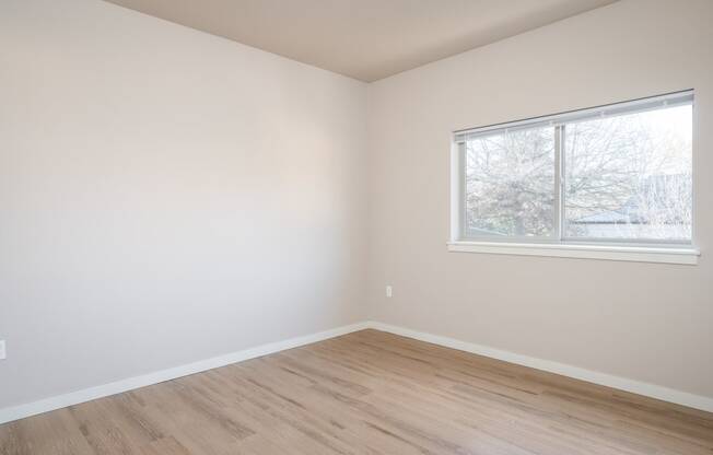 an empty room with wooden floors and a window