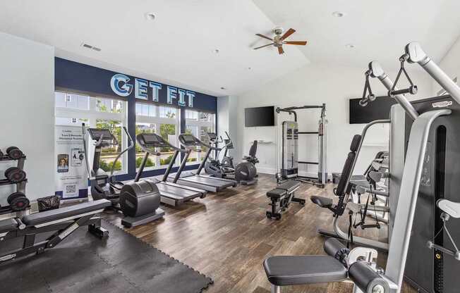 A gym with a variety of equipment including treadmills, weights, and exercise machines.