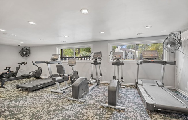 a gym with treadmills and exercise bikes in a room with a window