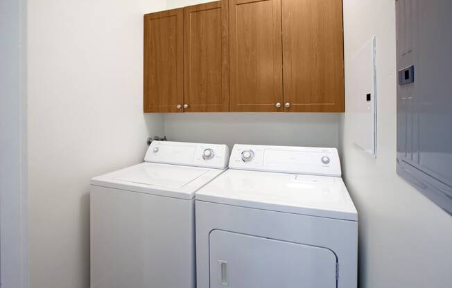 One and Two Bedroom Laundry Room with wall cabinets above side by side Washer and Dryer