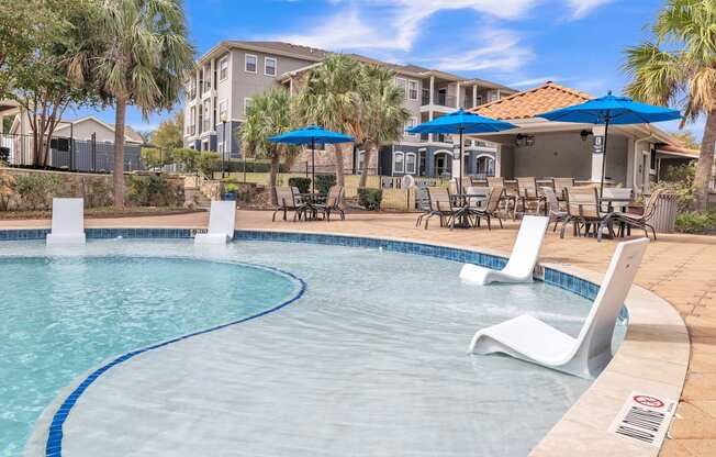 a swimming pool with chairs and umbrellas and a building in the background