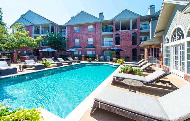 A swimming pool with an apartment building in the background at The Inverness Apartments in Houston, TX