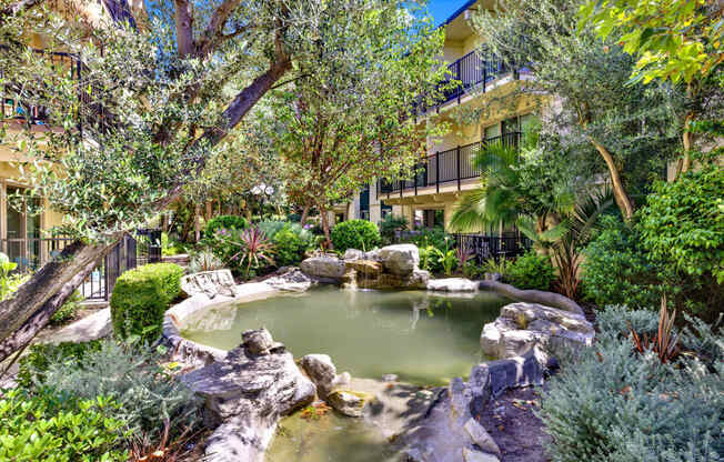 a pond in a garden with trees and rocks at Willow Tree Apartments, Torrance