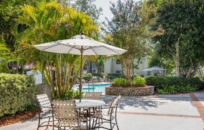 a patio with a table and chairs and a pool in the background